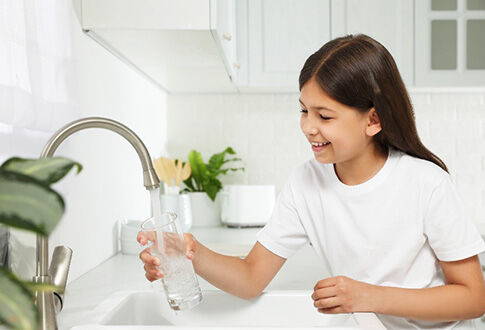 Jeune fille se servant un verre d'eau au robinet © 123rf